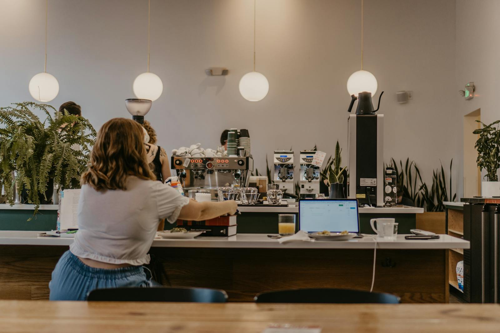 A woman works on a laptop at a coffee shop counter creating a productive workspace vibe.
